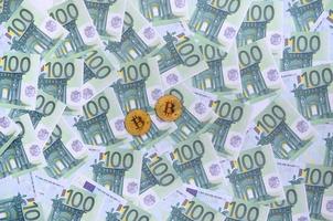los bitcoins físicos dorados se encuentran en un conjunto de denominaciones monetarias verdes de 100 euros. mucho dinero forma un montón infinito foto