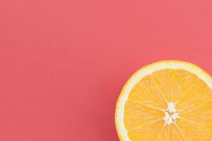 Top view of a one orange fruit slice on bright background in red color. A saturated citrus texture image photo