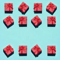 muchas pequeñas cajas de regalo de color rosa rojo sobre fondo de textura de papel de color azul pastel de moda en concepto mínimo. patrón abstracto foto