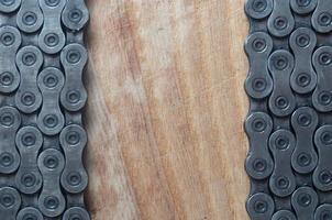 Dirty and oily chain from a mountain bike lying on a wooden table in a bicycle shop photo