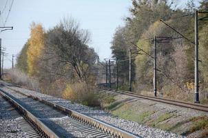 paisaje industrial de otoño. ferrocarril retrocediendo en la distancia entre árboles de otoño verdes y amarillos foto