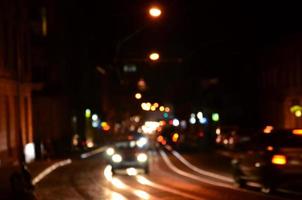 escena nocturna borrosa de tráfico en la carretera. imagen desenfocada de coches que viajan con faros luminosos. arte bokeh foto