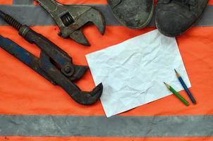 Adjustable wrenches with old boots and a sheet of paper with two pencils photo