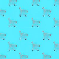 Shopping addiction, shopping lover or shopaholic concept. Many small empty shopping carts perform a pattern on a pastel colored paper background. Flat lay composition, top view photo