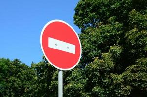 A circular red sign with a white bar indicating NO ENTRY on a grey metal post photo