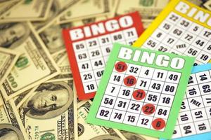 Many bingo boards or playing cards for winning chips and big amount of dollar bills. Classic american or canadian five to five bingo cards on money photo