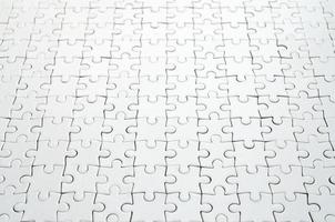 Close up of a white jigsaw puzzle in assembled state in perspective. Many components of a large whole mosaic are united photo