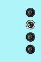 A few camera lenses with a closed aperture lie on texture background of fashion pastel blue color paper photo