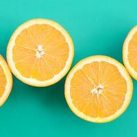 Top view of a several orange fruit slices on bright background in turquoise green color. A saturated citrus texture image photo