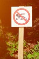 A pillar with a sign denoting a ban on swimming. The sign shows a crossed-out floating person photo