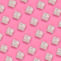 un montón de cajas de regalo rosas se encuentran en el fondo de textura de papel de color rosa pastel de moda en un concepto mínimo. patrón abstracto de moda foto