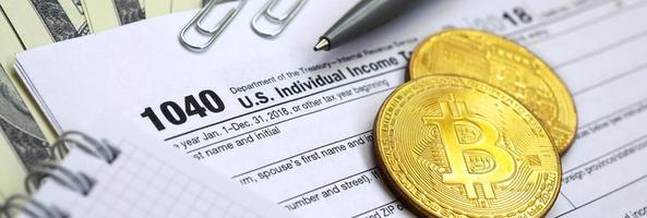 The pen, bitcoins and dollar bills is lies on the tax form 1040 U.S. Individual Income Tax Return. The time to pay taxes photo