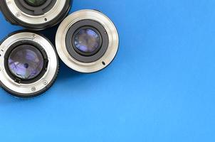 Several photographic lenses lie on a bright blue background. Space for text photo