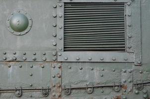 Texture of tank side wall, made of metal and reinforced with a multitude of bolts and rivets photo