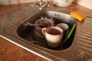 Stack of dirty dishes with food leftovers in the kitchen sink. Unwashed dishes photo