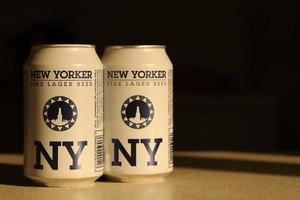 TERNOPIL, UKRAINE - JULY 18, 2022 Two cans of New Yorker fine lager beer with original logo and design on brown retro background photo