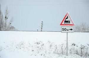 Railway crossing without barrier. A road sign depicting an old black locomotive, located in a red triangle photo