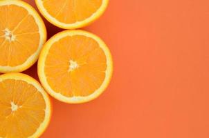 Top view of a several orange fruit slices on bright background in orange color. A saturated citrus texture image photo