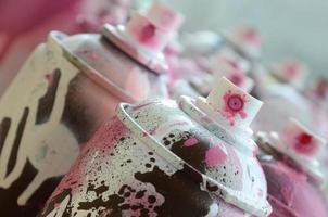 A lot of dirty and used aerosol cans of bright pink paint. Macro photograph with shallow depth of field. Selective focus on the spray nozzle photo