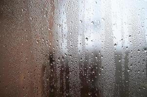 una foto de la superficie de vidrio de la ventana, cubierta con una multitud de gotas de varios tamaños. textura de fondo de una densa capa de condensado sobre vidrio