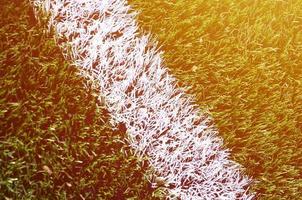 White stripe on a bright green artificial grass soccer field photo