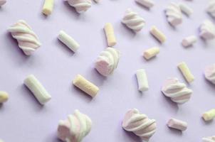 Colorful marshmallow laid out on violet paper background. pastel creative textured pattern. Perspective macro shot photo