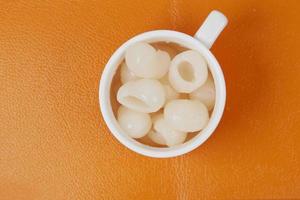 longans fruits in cup on orange background photo