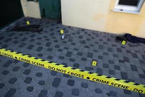 Crime scene tape for covering the area cordon. Yellow tape with blurred forensic law enforcement background in cinematic tone photo