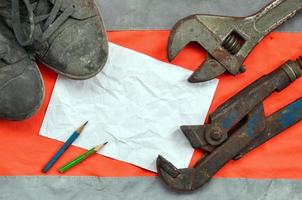 Adjustable wrenches with old boots and a sheet of paper with two pencils photo