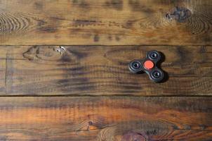 A rare handmade wooden fidget spinner lies on a brown wooden background surface. Trendy stress relieving toy photo
