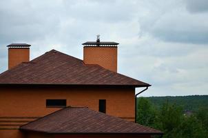 la casa está equipada con techos de tejas bituminosas de alta calidad. un buen ejemplo de techado perfecto. el techo está protegido de manera confiable contra condiciones climáticas adversas foto