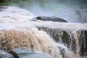 peligros prohibidos para persona jugar agua. tormenta ráfagas de la peligrosa inundación repentina de la cascada en la temporada de lluvias. Las mareas impactan la piedra que hace que la presión del agua fluya rápidamente. foto