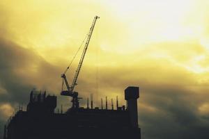 The tower crane is lifting things at the construction site. photo