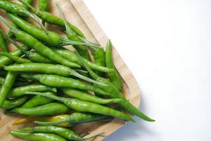 close up of green chili on a chopping board on white background photo