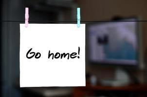 Go home Note is written on a white sticker that hangs with a clothespin on a rope on a background of office interior photo