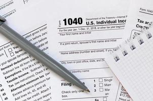 The pen and notebook is lies on the tax form 1040 U.S. Individual Income Tax Return. The time to pay taxes photo