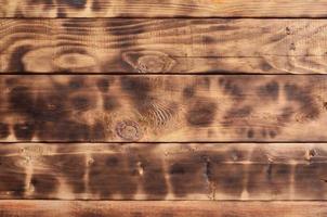 The texture of the scorched wooden wall. Wall of smooth orange long wooden boards with a specific black texture of frying photo