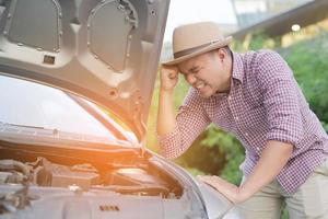 young stressed man having trouble with his broken car stand in front a broken car calling for assistance. photo