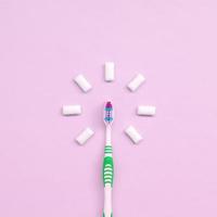 Toothbrush and chewing gums lie on a pastel pink background photo