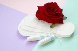 Menstrual pads and tampons with red rose flower on multicolored background photo