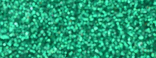 A huge amount of green decorative sequins. Blurred background image with shiny bokeh lights from small elements that reflect light in a random order photo