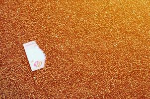 Background texture of a large pile of buckwheat, among which one can see a bill of one Ukrainian hryvnia. The concept of increasing prices for cereals in Ukraine photo