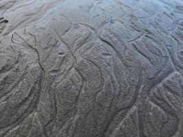 This is a picture of a background of sand on the beach that has just been washed away by the waves photo