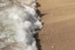 Blurred background, breaking wave on the sandy shore, top view. Background. photo