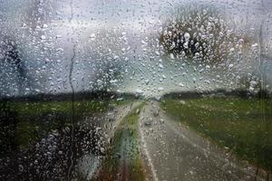 ventana lluviosa, gotas de lluvia sobre el vidrio en el fondo de la autopista. camino seguro a casa. foto