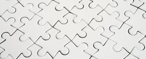 Close up of a white jigsaw puzzle in assembled state in perspective. Many components of a large whole mosaic are united photo