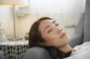 Young asian woman napping on the sofa in living room , happy healthy lifestyle concept photo