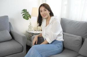 Portrait of young asian woman smiling on sofa in living room photo