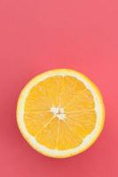 Top view of a one orange fruit slice on bright background in red color. A saturated citrus texture image photo