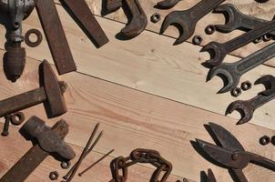 A set of old and rusty tools lies on a wooden table in the workshop photo